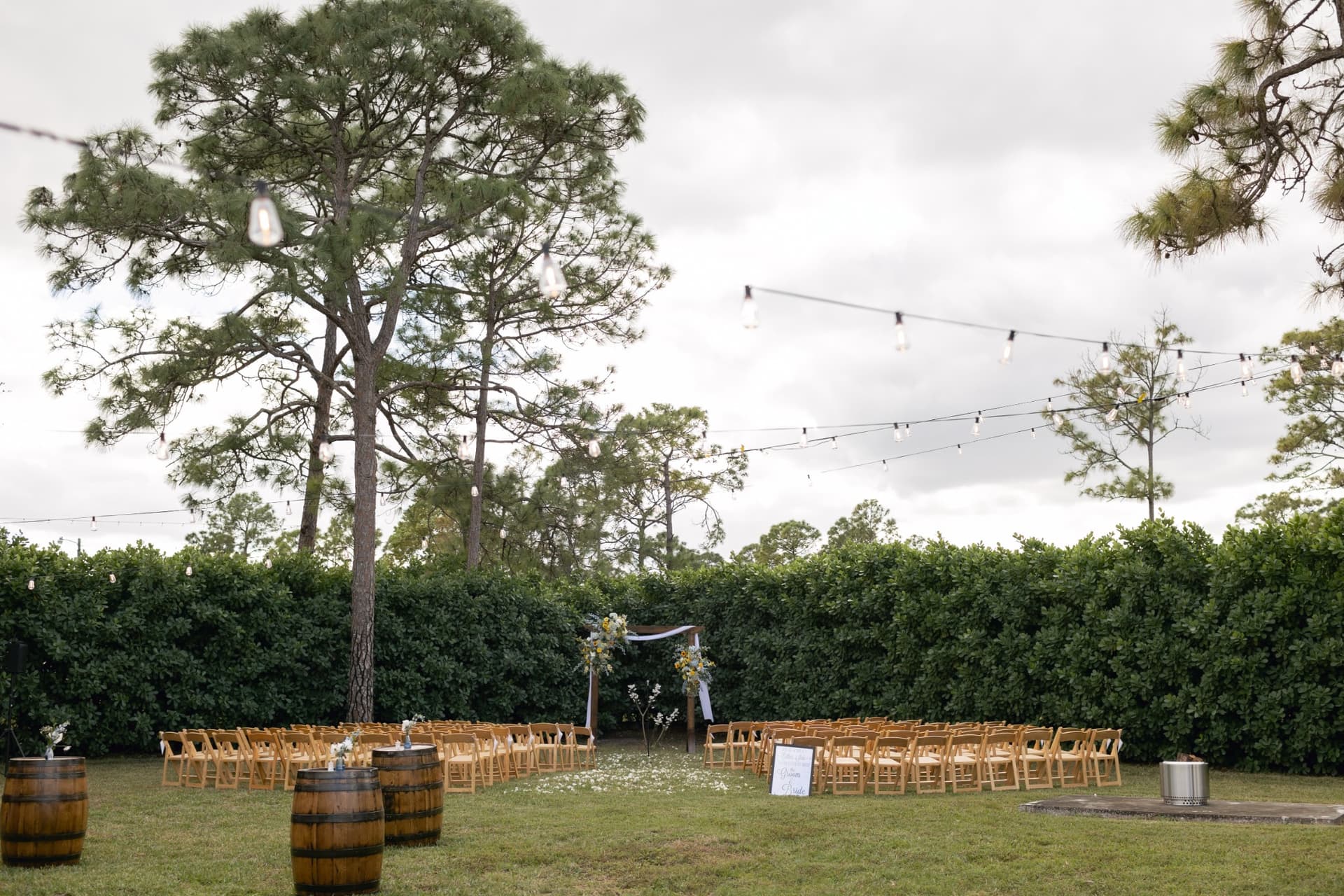 Outdoor ceremony with barrels in front and wedding arch in background