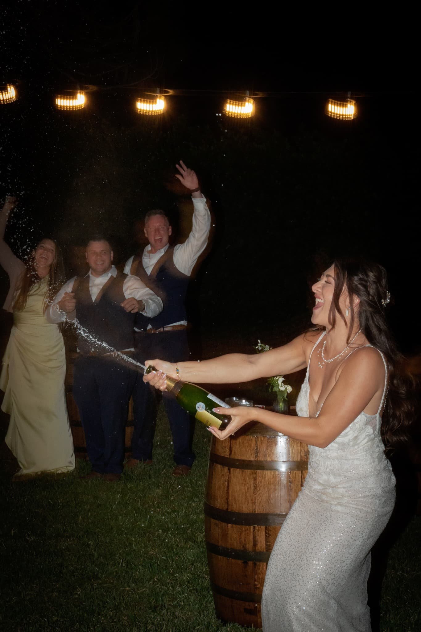 Bride popping champagne beside a whiskey barrel at a Palm Beach wedding